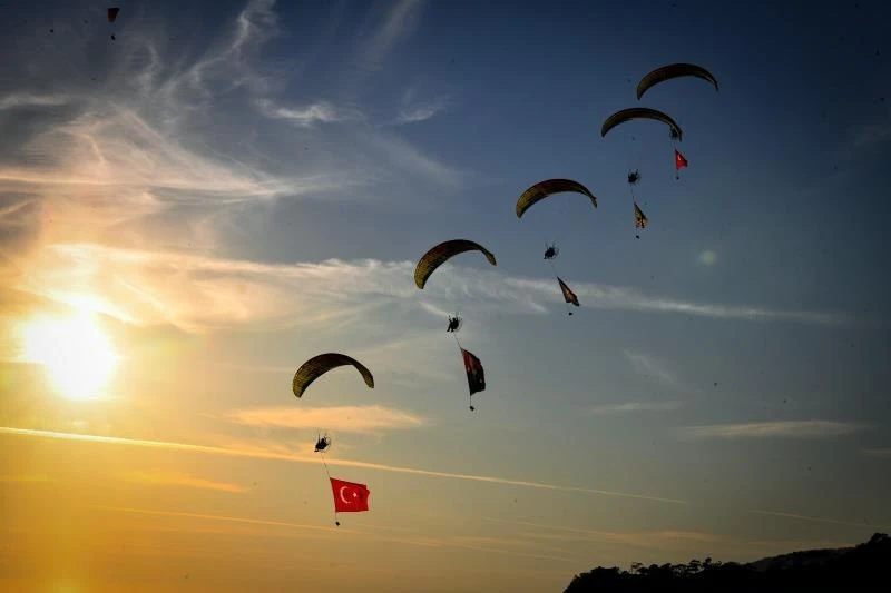 Gün batımında Türk bayrağı taşıyan motorlu yamaç paraşütleri, Ölüdeniz Hava Oyunları Festivali