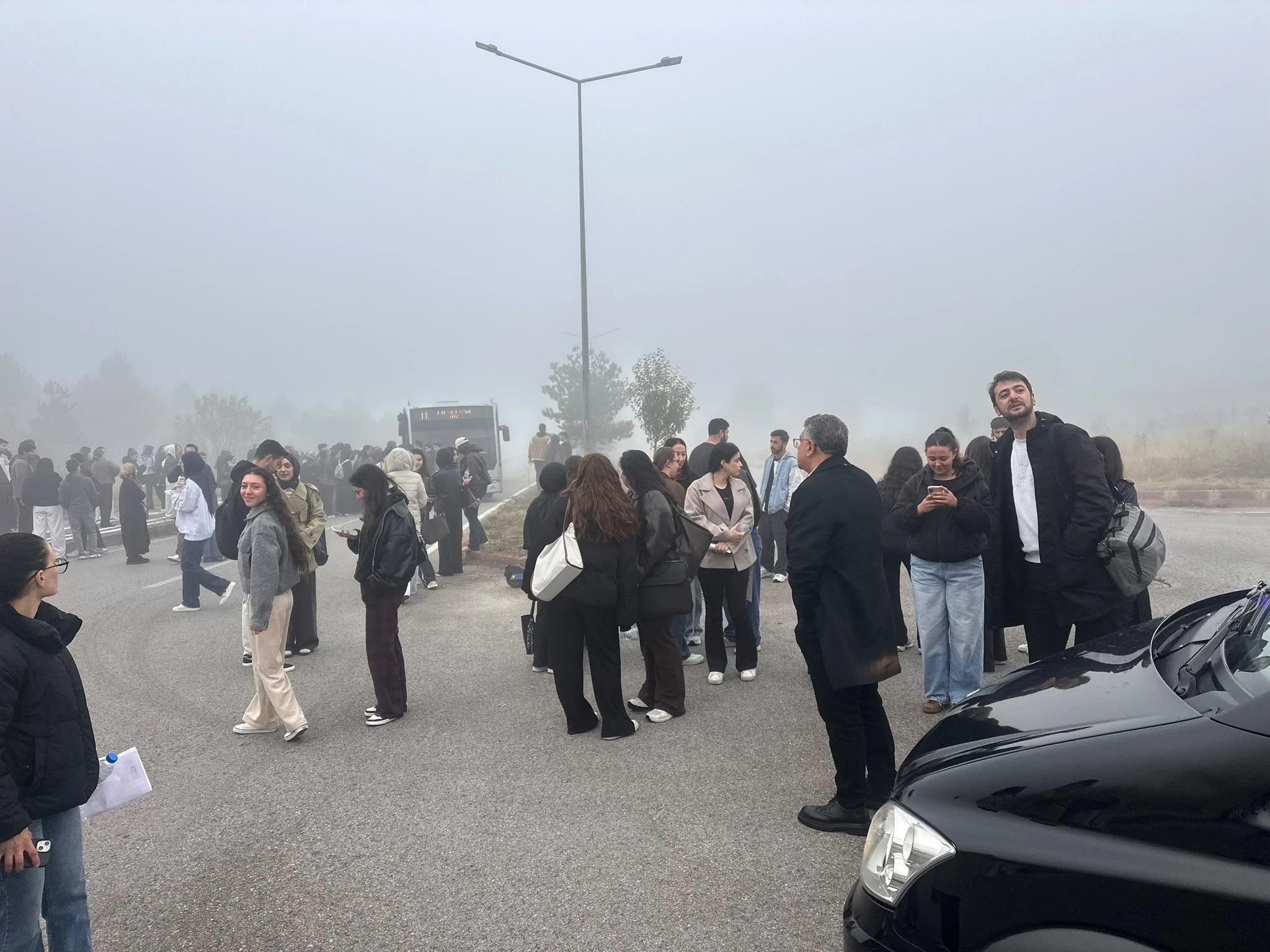 Kütahya Dumlupınar Üniversitesi Evliya Çelebi Yerleşkesi'nde sisli sabah otobüs bekleyen KPSS adayları