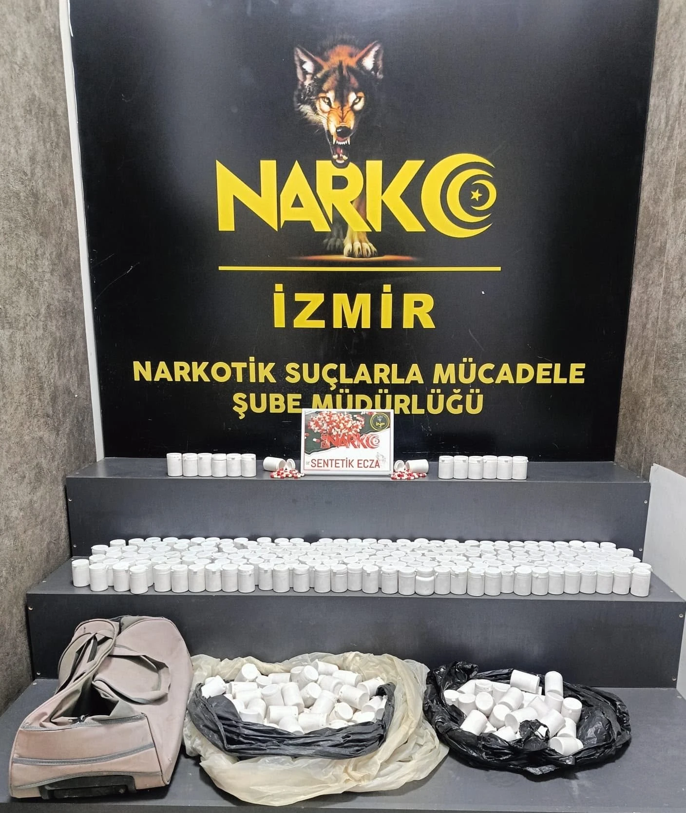 İzmir Torbalı'da ele geçirilen sentetik hap kutuları ve çanta Narkotik Şube önünde sergileniyor