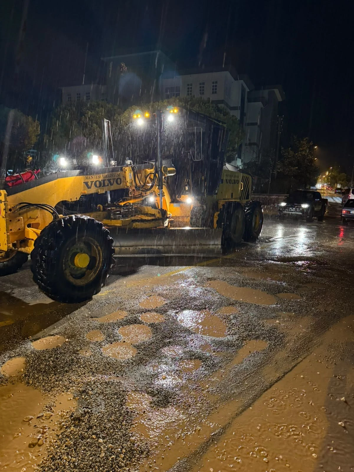 Muğla'da gece saatlerinde su biriken yolda çalışan Muğla Büyükşehir Belediyesi iş makinesi
